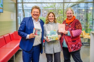 Gesundheitsminister Dr. Andreas Philippi, Laura Klocker und Dr. Corinna Morys-Wortmann (Gesundheitsregion Göttingen/Südniedersachsen) präsentieren die geöffnete LuckyMotion-Box und halten Karten in den Händen